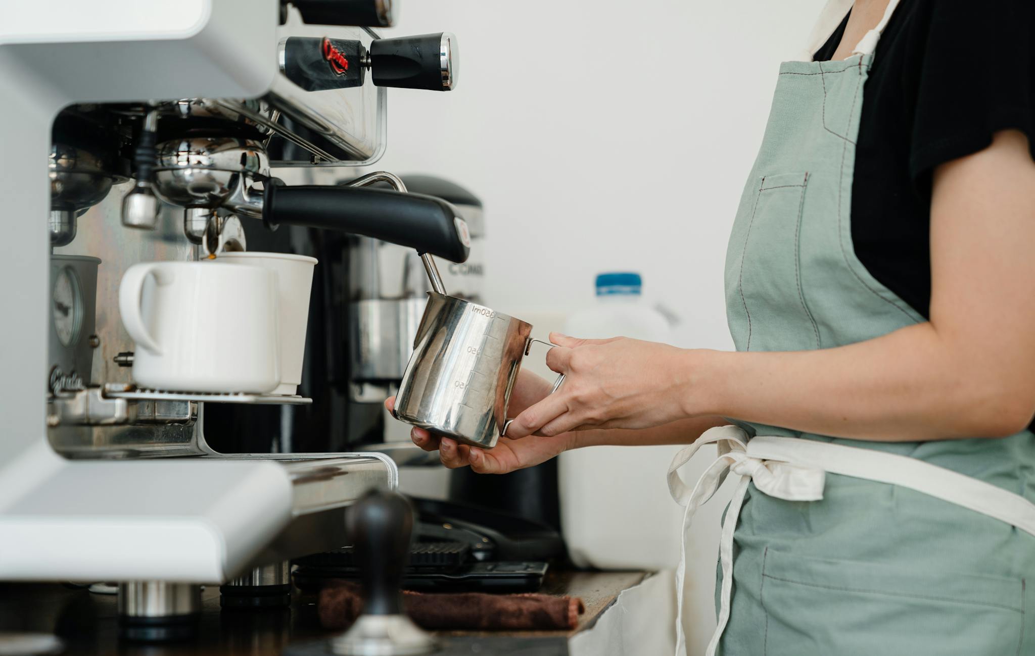 Rockies Line Crop young barista preparing fresh latte in cafe